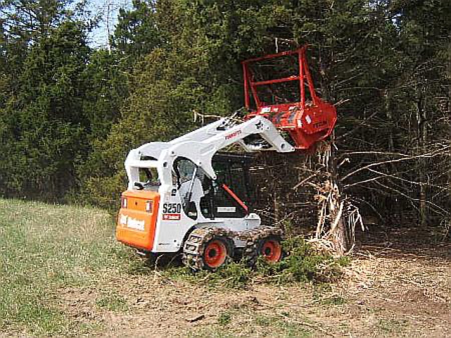 Skid steer forestry mulcher cutting dense roadside brush